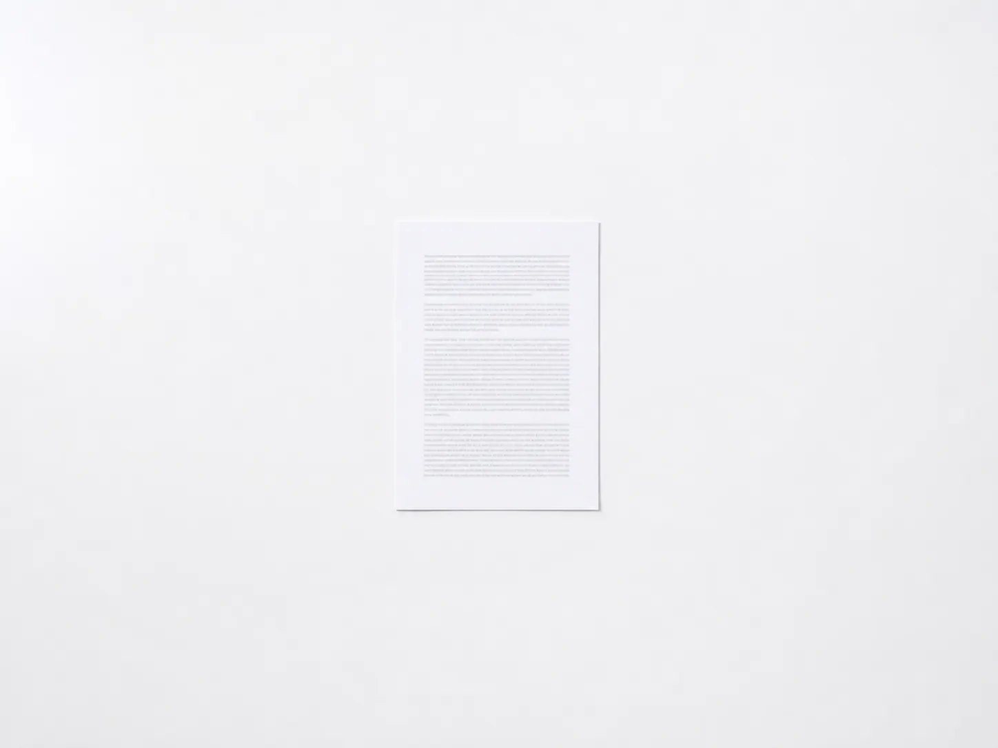 A single printed sheet alone at the centre of an otherwise empty pale surface.